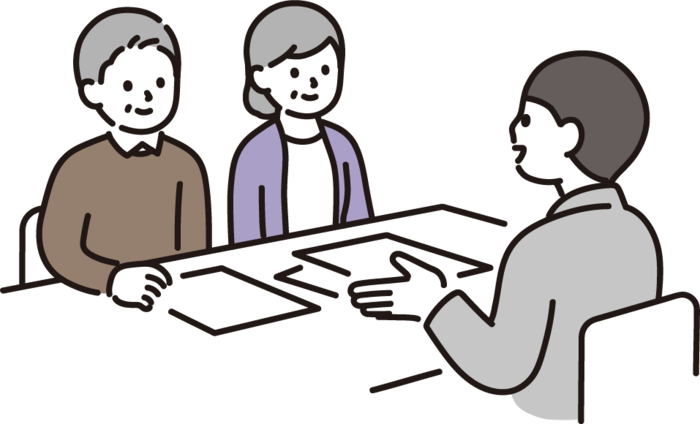 Un hombre está sentado en una mesa proponiendo algo a dos personas, un hombre y una mujer.